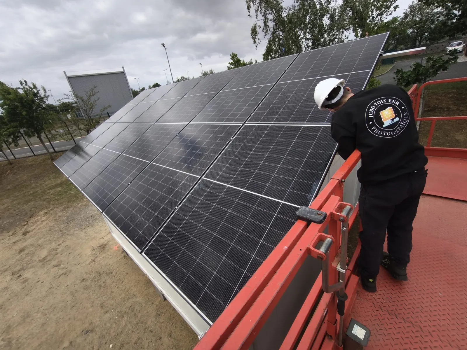 Technicien JCBO Toit ENR posant des panneaux photovoltaïques depuis une nacelle